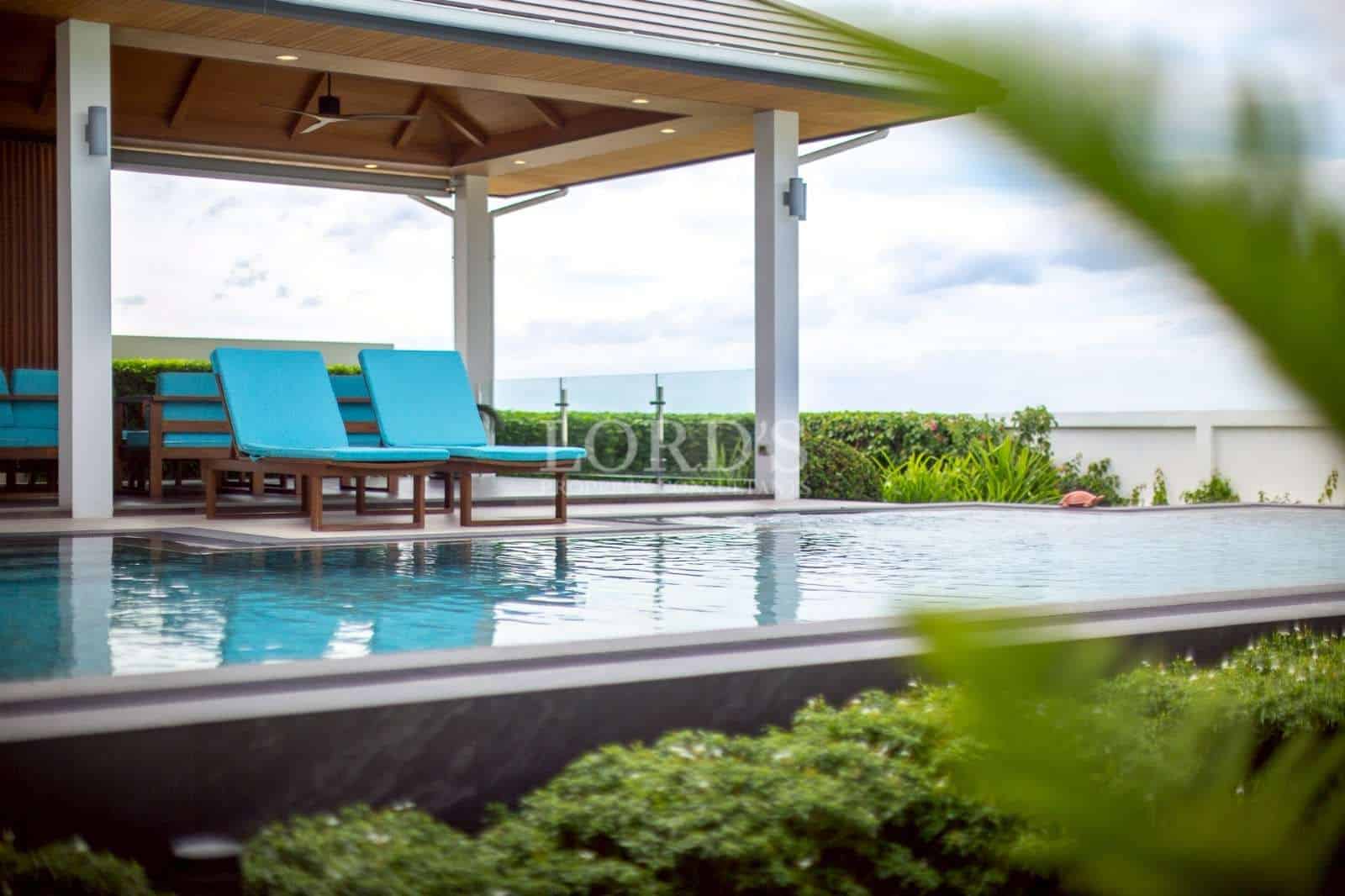 Luxury outdoor swimming pool with covered terrace and sun loungers.