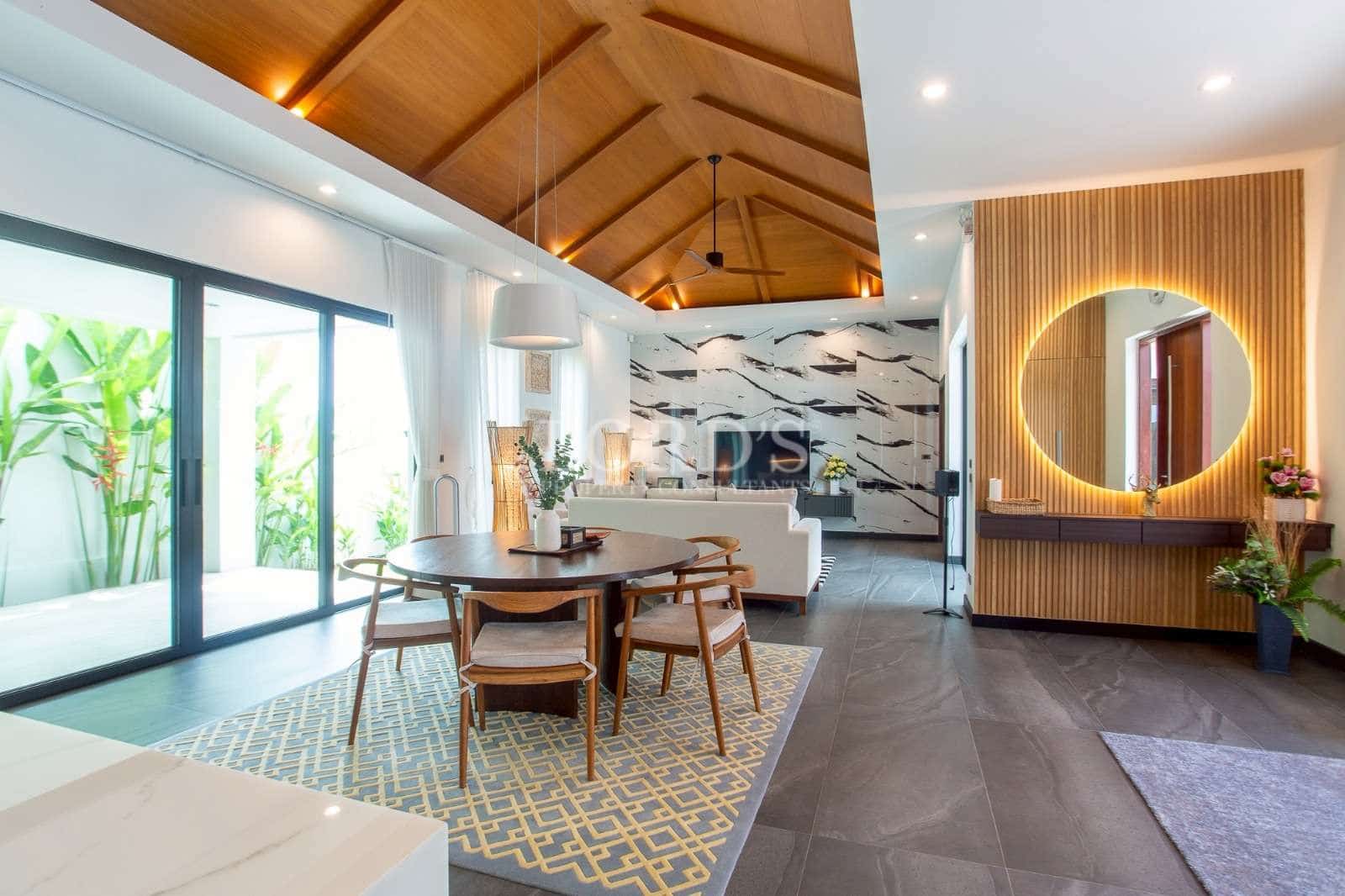 Modern open-plan living and dining area with vaulted wooden ceiling, sliding glass doors, and accent wall mirror.