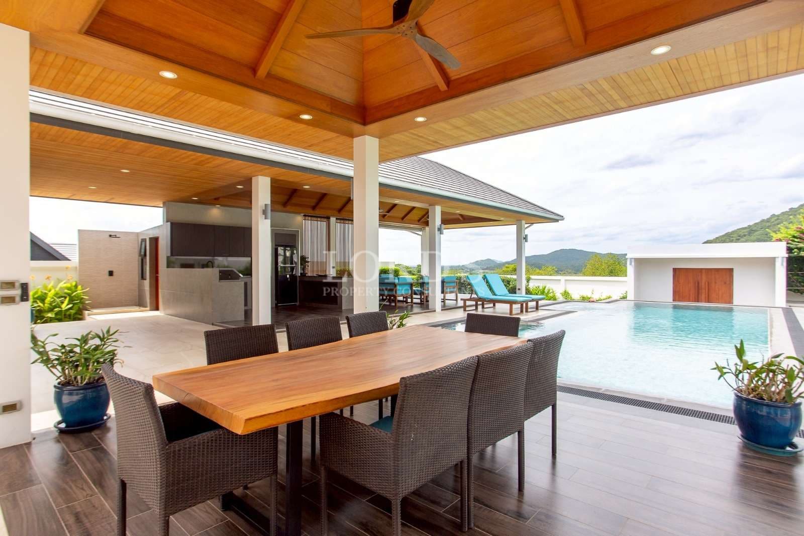 Luxury outdoor dining area with wooden table, covered pavilion, and private swimming pool.