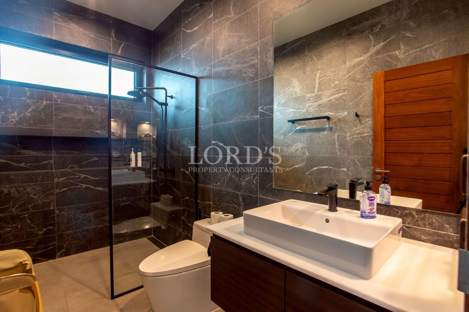 Modern luxury bathroom with glass shower, marble tiles, and contemporary vanity.