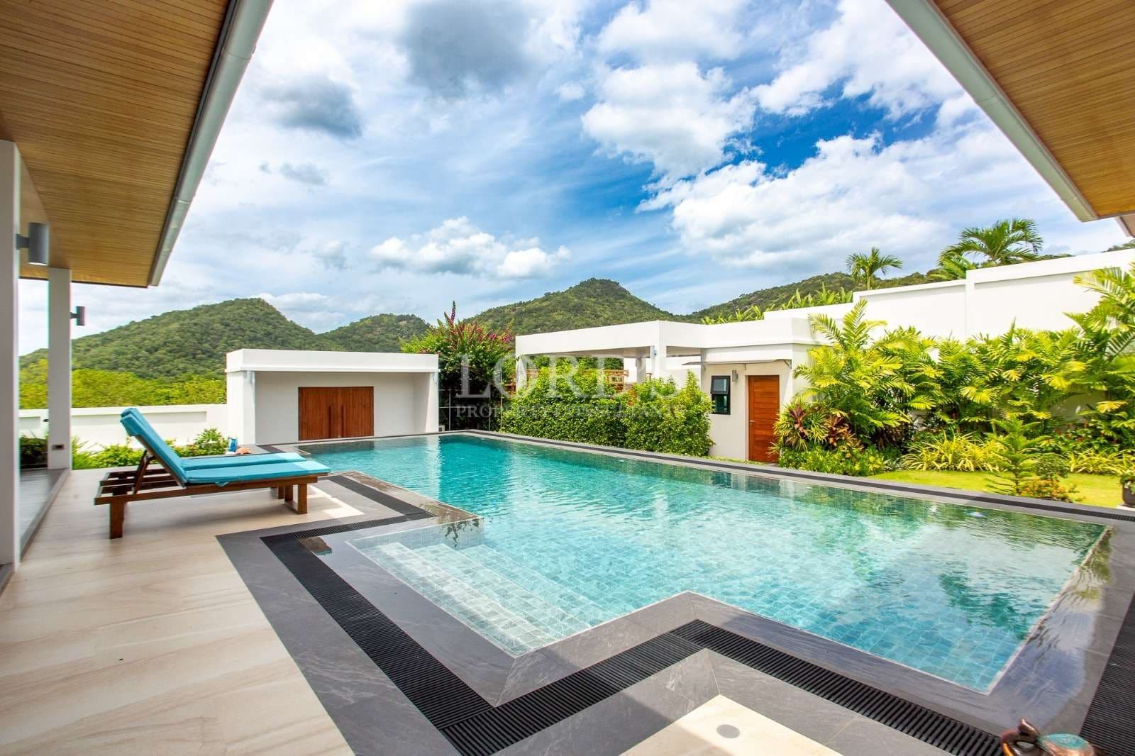 Private luxury swimming pool with sun lounger, tropical garden, and mountain views.