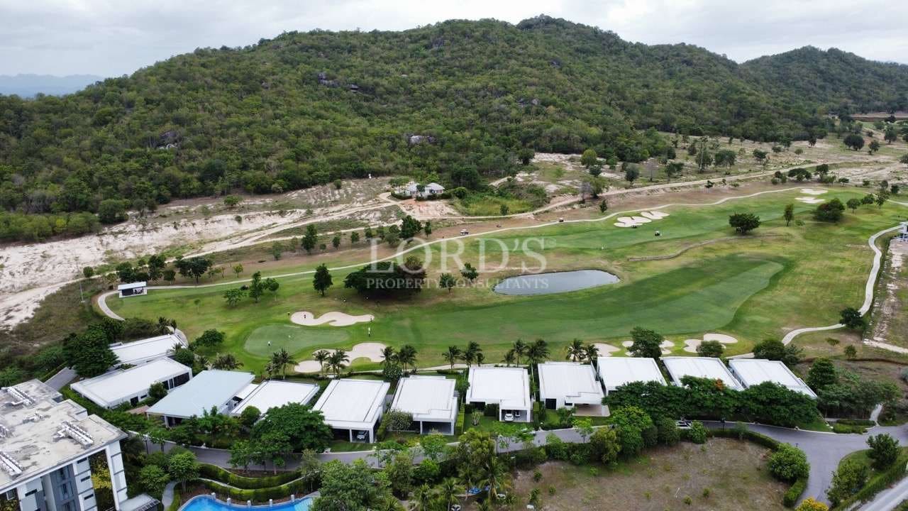 Aerial view of golf course fairway with luxury villas and mountain landscape