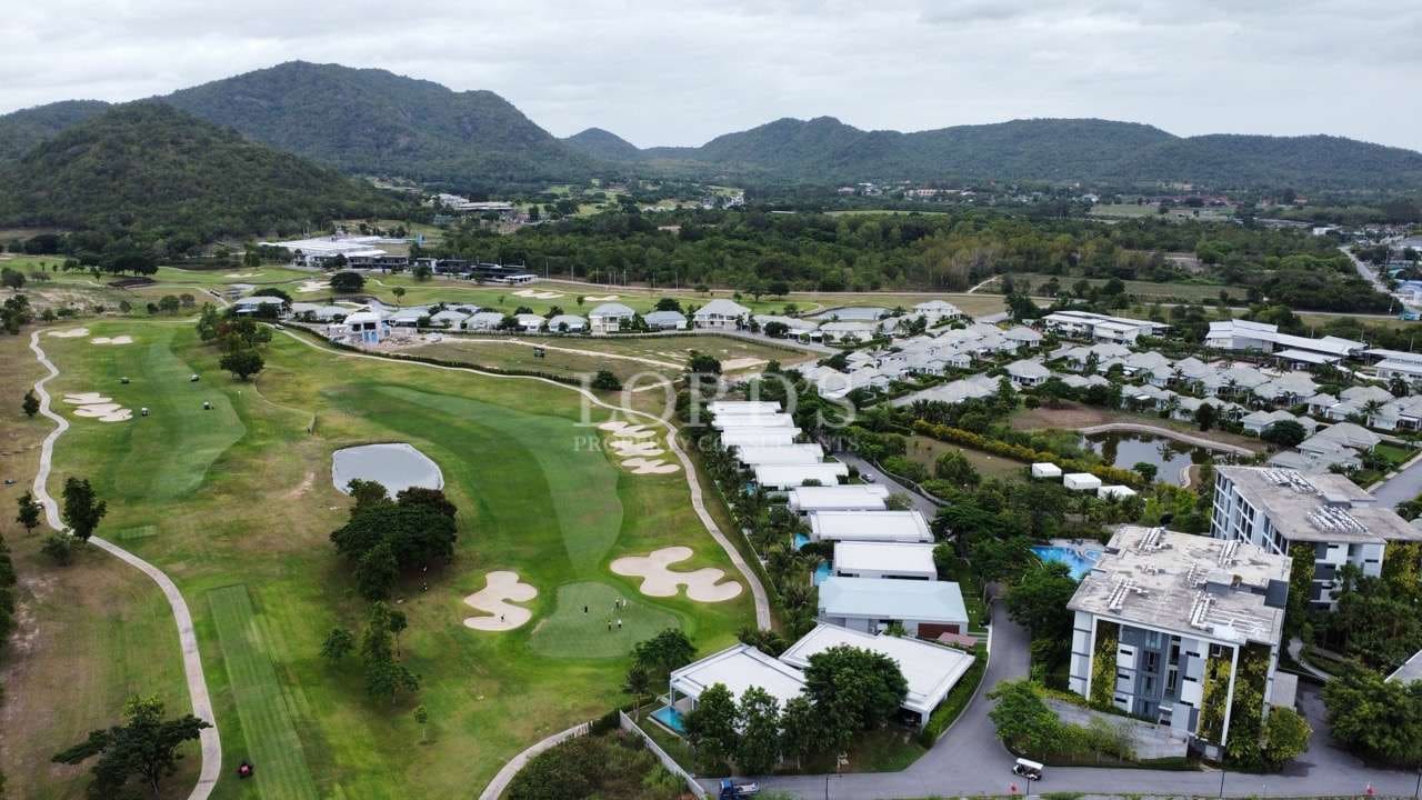 Aerial view of luxury golf course community with villas, fairways, and mountain backdrop