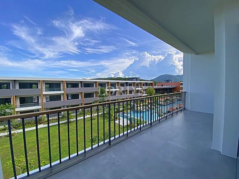 Private apartment balcony with tiled flooring overlooking landscaped gardens, swimming pool, and modern residential buildings.
