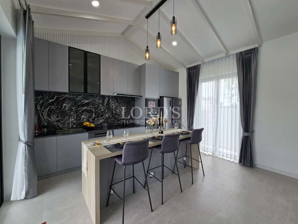 Modern open-plan kitchen with gray cabinetry, marble backsplash, and island dining bar.