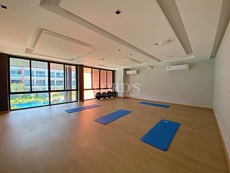 Yoga and fitness studio with wooden flooring, yoga mats, recessed ceiling lights, and large windows.
