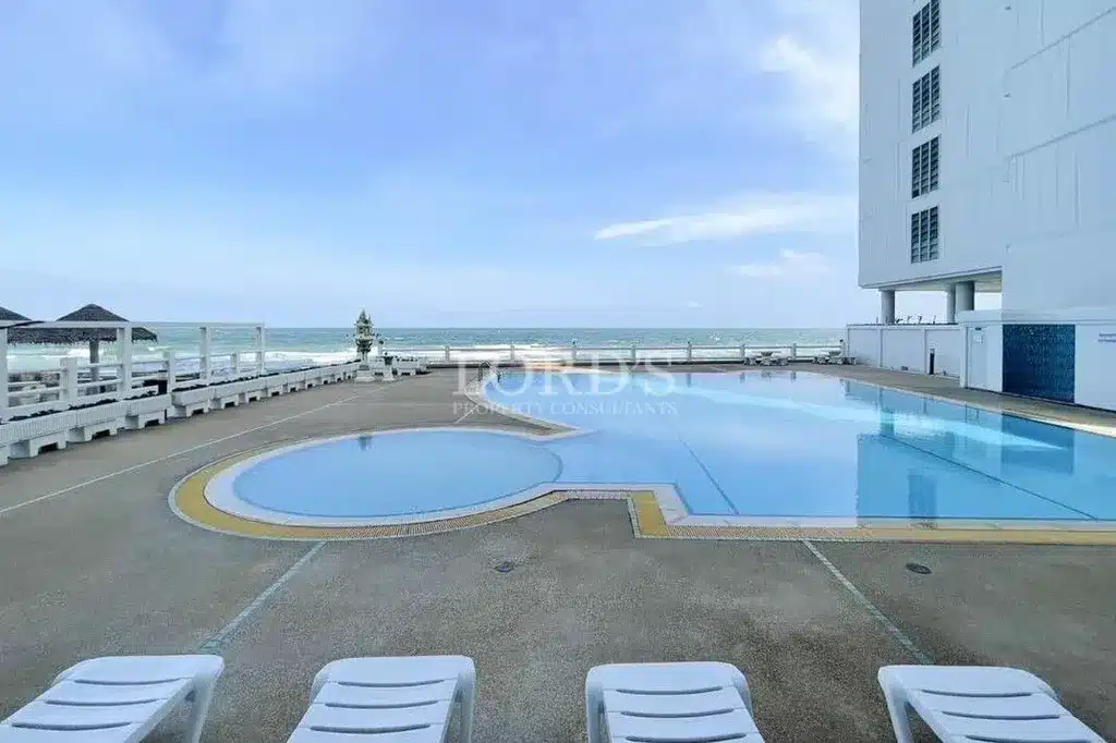 Oceanfront swimming pool with sun loungers overlooking the sea.