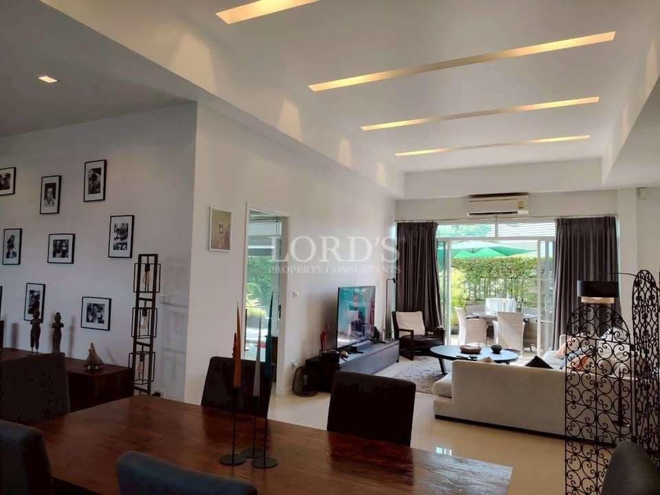 Open-plan living and dining area with modern furniture, recessed ceiling lighting, wall art, and garden views.