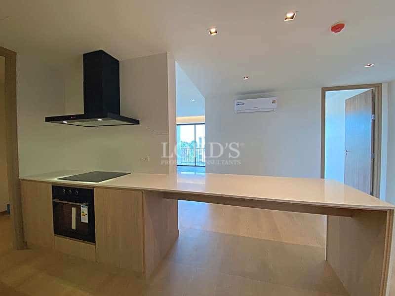 Modern open kitchen with white island countertop, built-in oven, induction cooktop, black range hood, and wooden cabinetry.