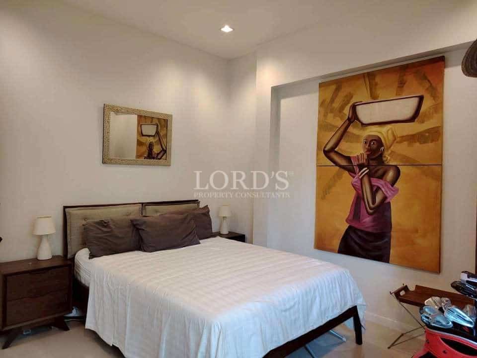 Modern bedroom with double bed, bedside tables, warm lighting, and large artistic wall painting.