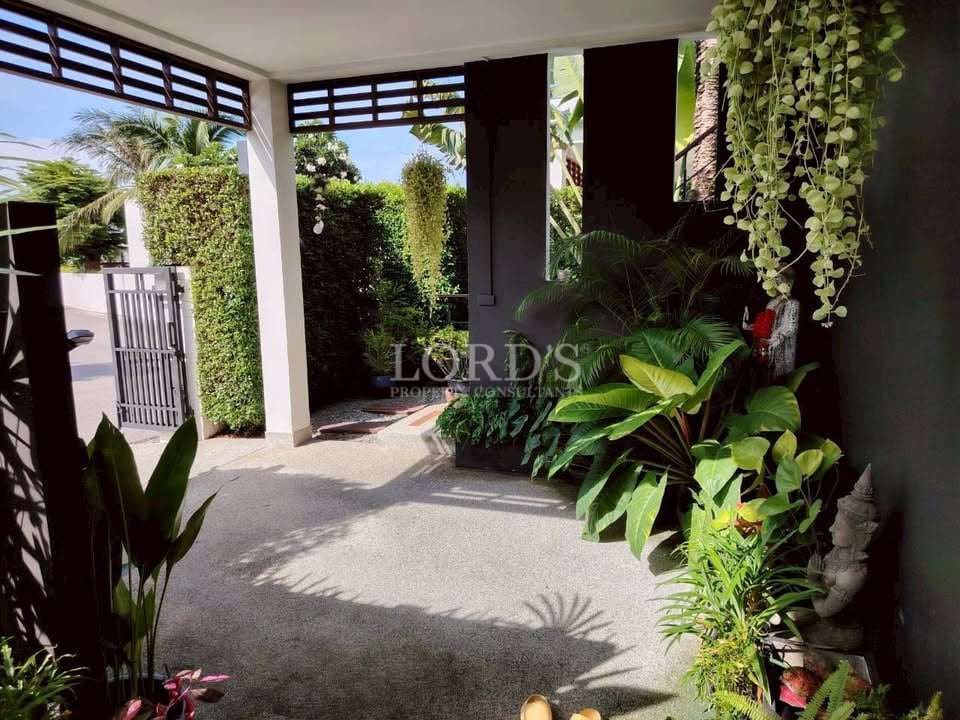 Private tropical entrance with lush greenery, covered walkway, and modern gated access.