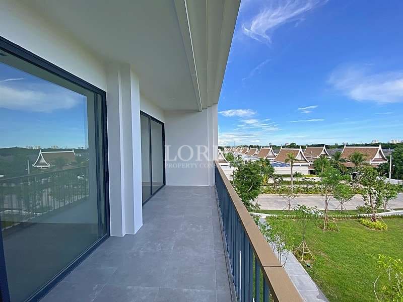 Private apartment balcony with tiled flooring and sliding glass doors overlooking green spaces and residential rooftops.