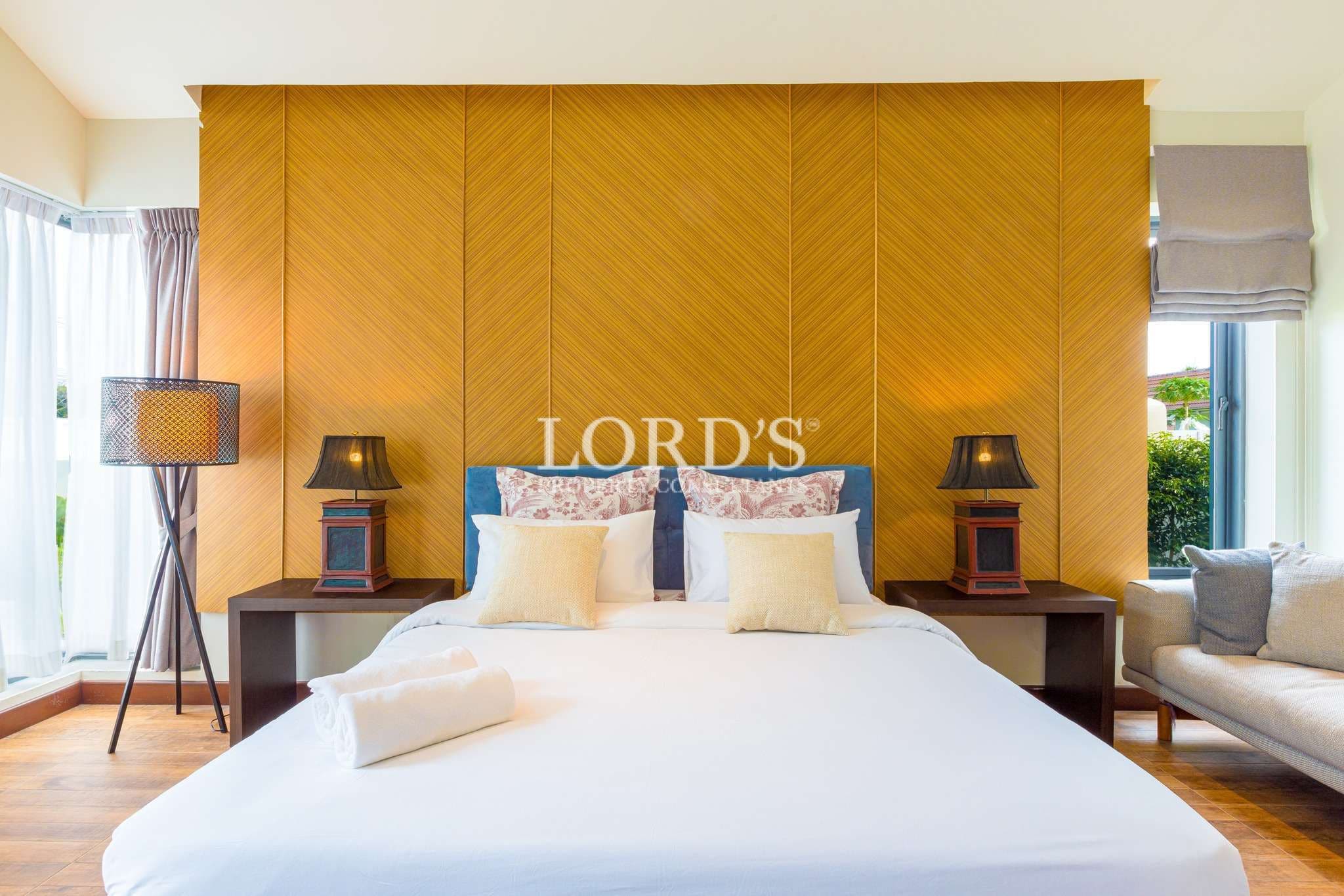 Elegant bedroom with king-size bed, wooden accent wall, bedside tables, and soft ambient lighting.