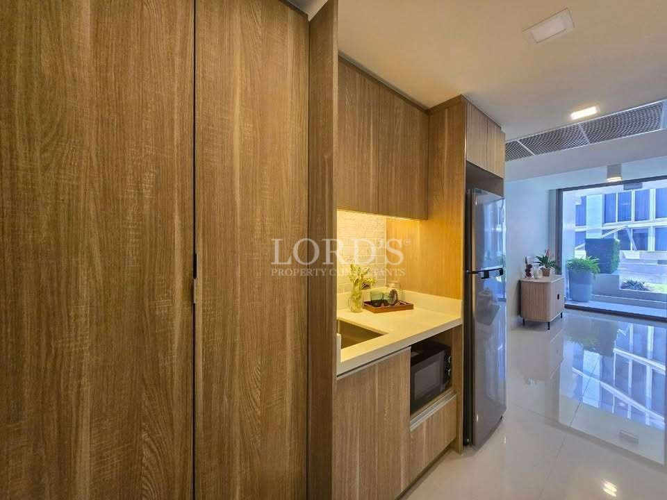 Modern compact kitchen with wood-finish cabinets, built-in appliances, and sleek countertop.