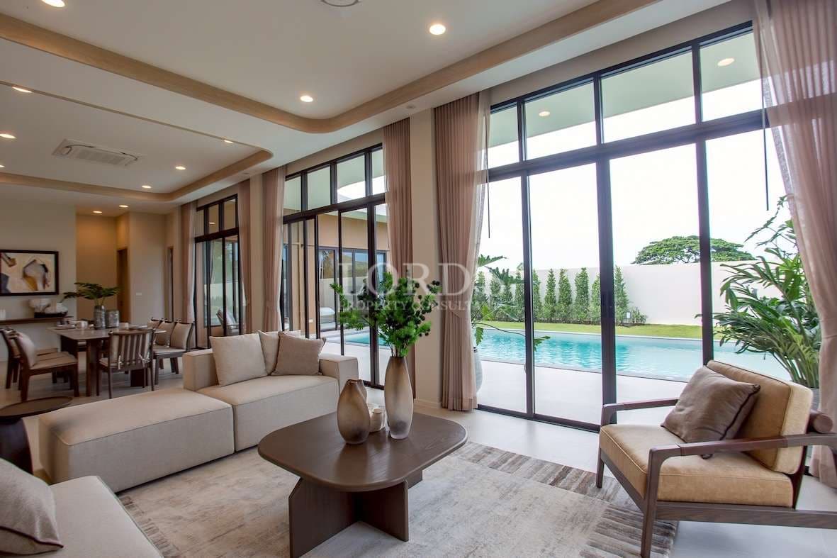 Spacious living room with floor-to-ceiling glass doors, modern furniture, and pool view.