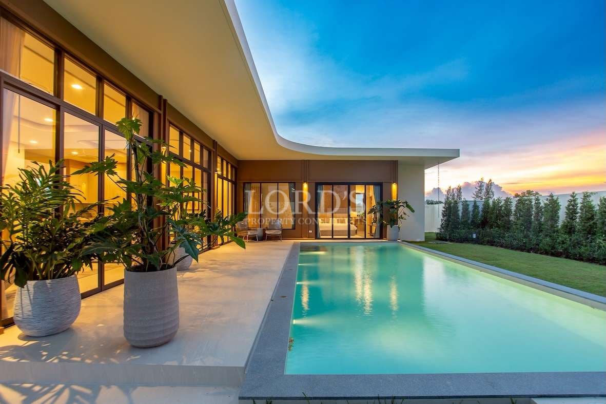 Modern luxury villa with private swimming pool, landscaped garden, and sunset lighting.