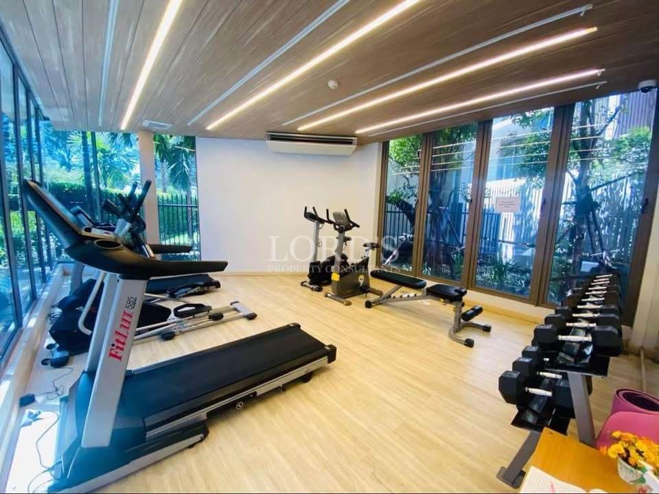 Modern fitness center with treadmills, exercise bikes, dumbbell rack, and large glass windows.