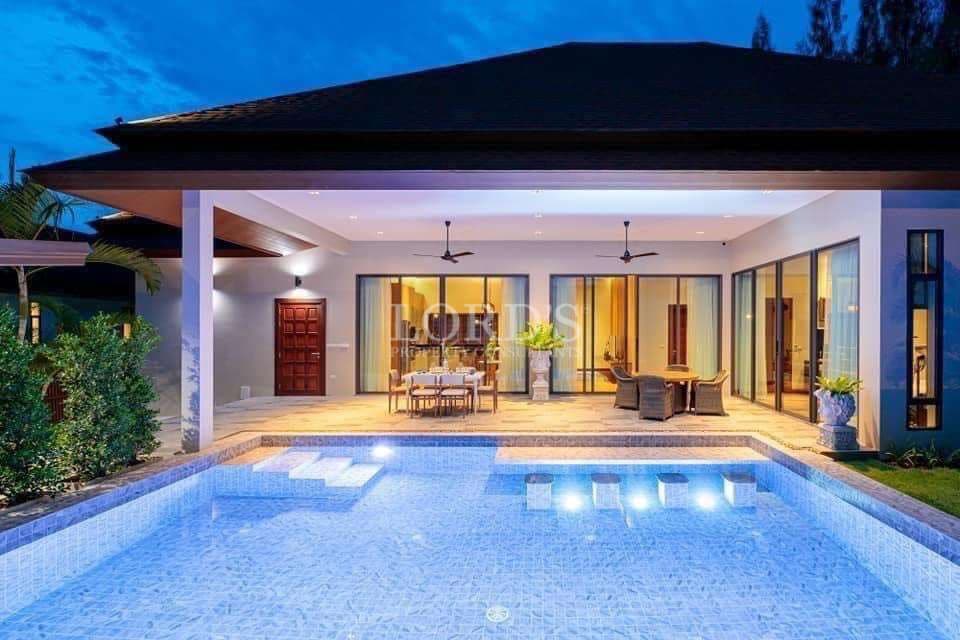 Modern luxury villa with private swimming pool, covered terrace, and outdoor dining area at night.