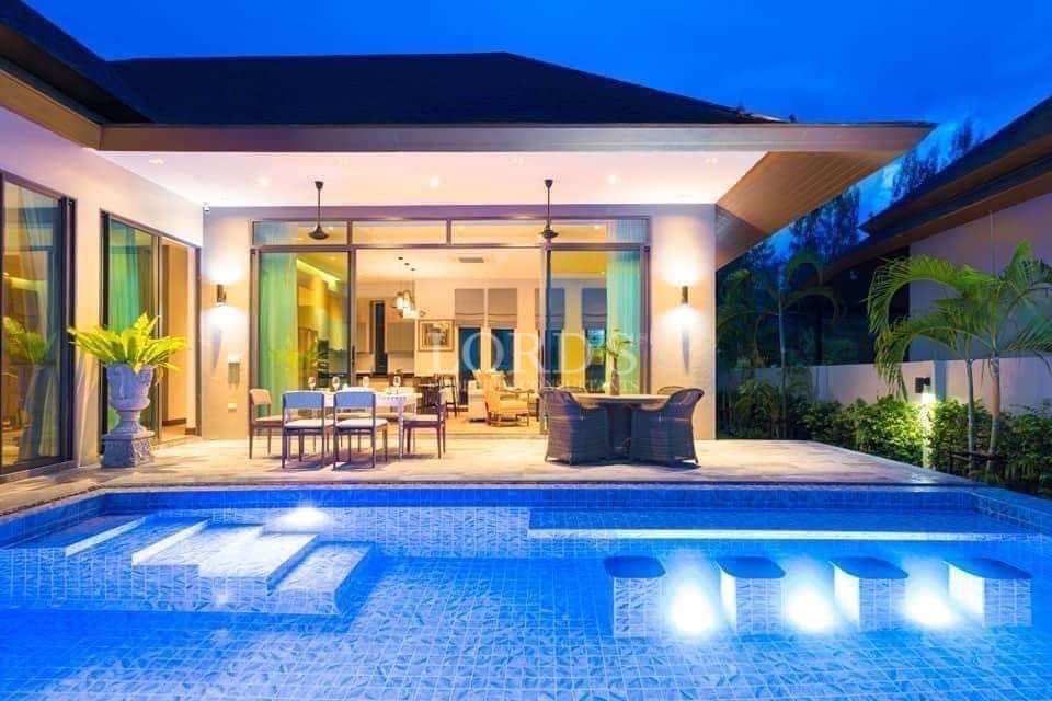 Luxury modern villa with private swimming pool, outdoor dining area, and evening ambient lighting.