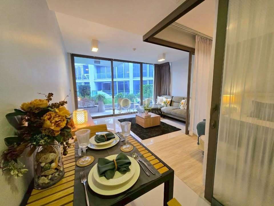 Modern open-plan apartment with dining table, living area, large glass doors, and balcony view.