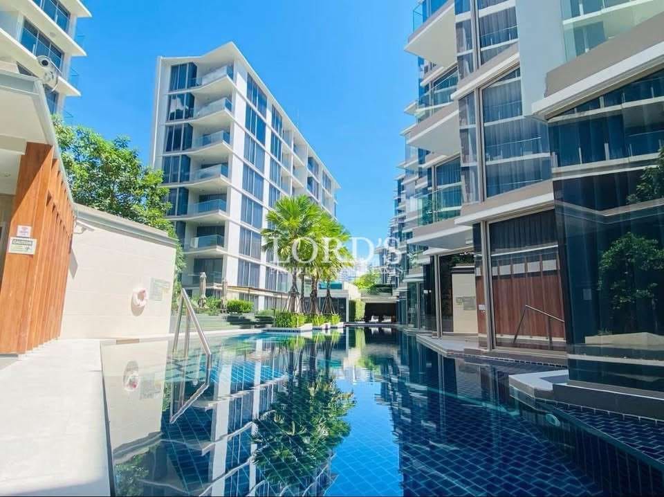 Modern condominium complex with swimming pool and glass balconies.
