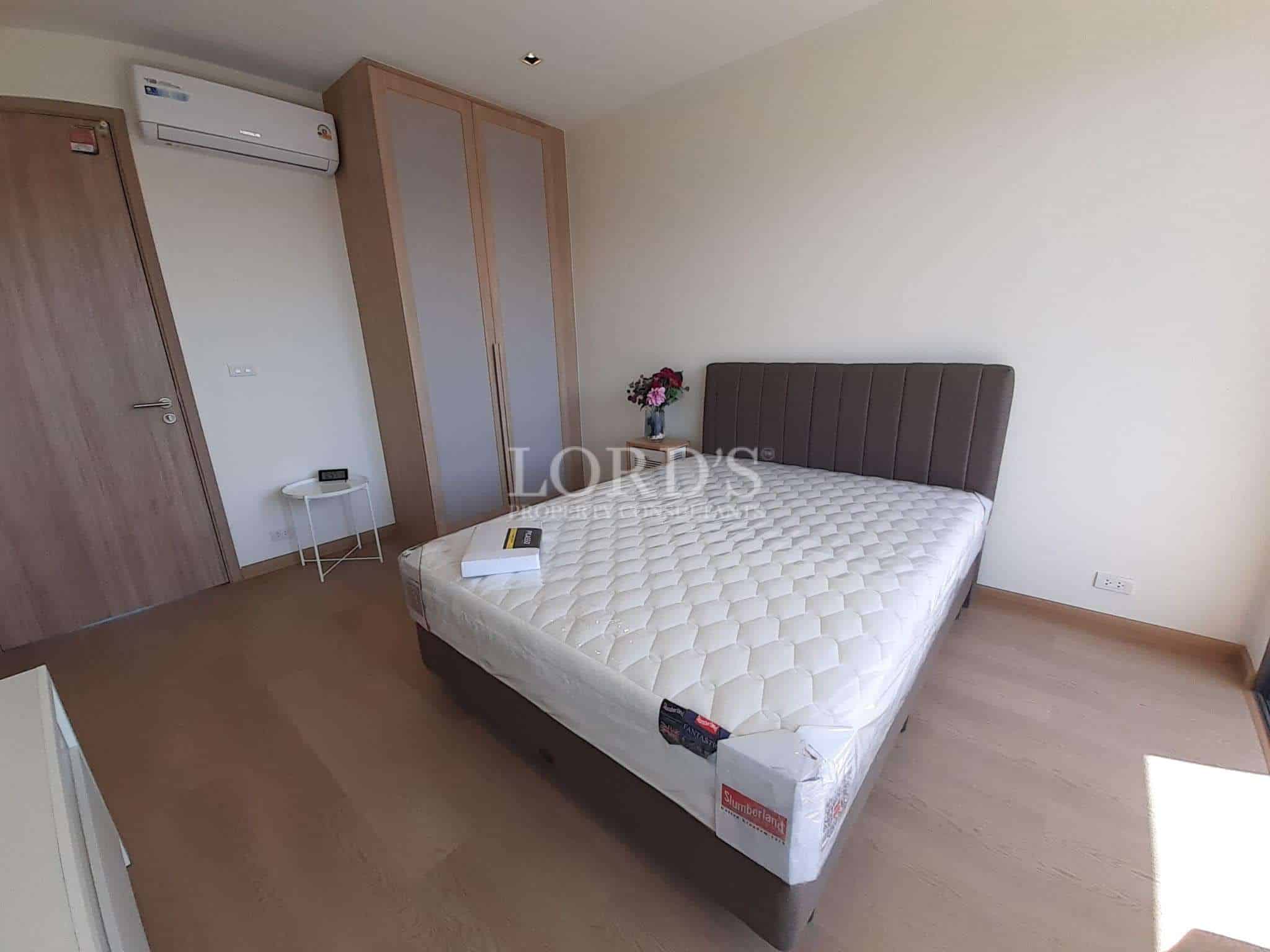Modern bedroom with double bed, padded headboard, wooden floor, built-in wardrobe, and air conditioning