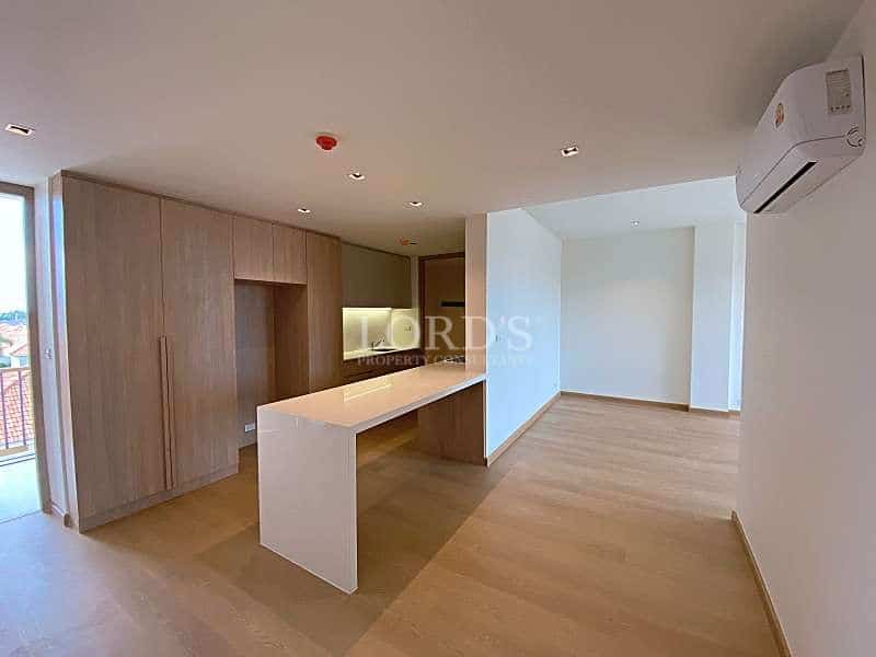 Open-plan living area with modern kitchen island, built-in wooden cabinetry, wooden flooring, and air conditioning.