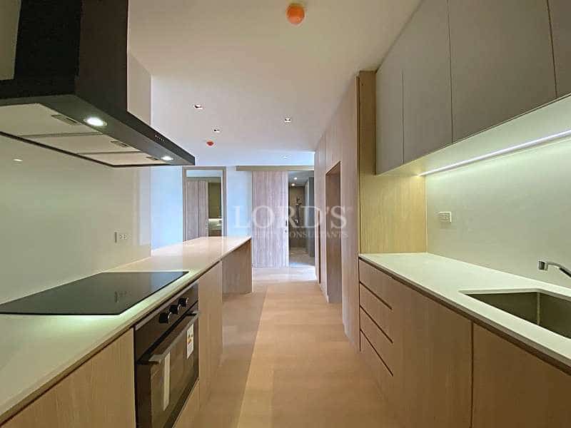 Modern galley kitchen with built-in oven, induction cooktop, integrated cabinetry, and white countertops.