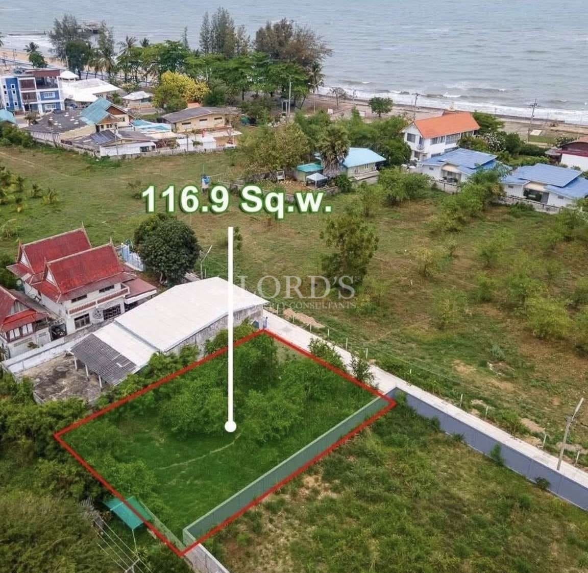 Aerial view of a 116.9 square wah land plot outlined in red near the beach in a coastal residential area.