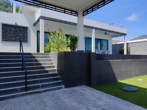Modern luxury house exterior with elevated terrace, outdoor steps, landscaped garden, and contemporary design.