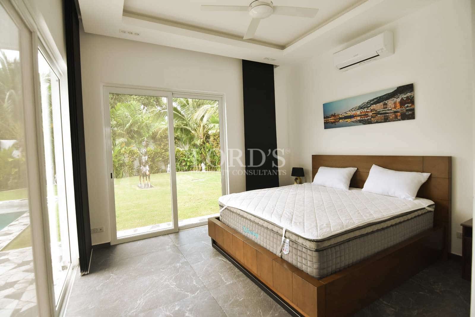 Modern bedroom with king-size bed, sliding glass doors, garden view, and air conditioning.