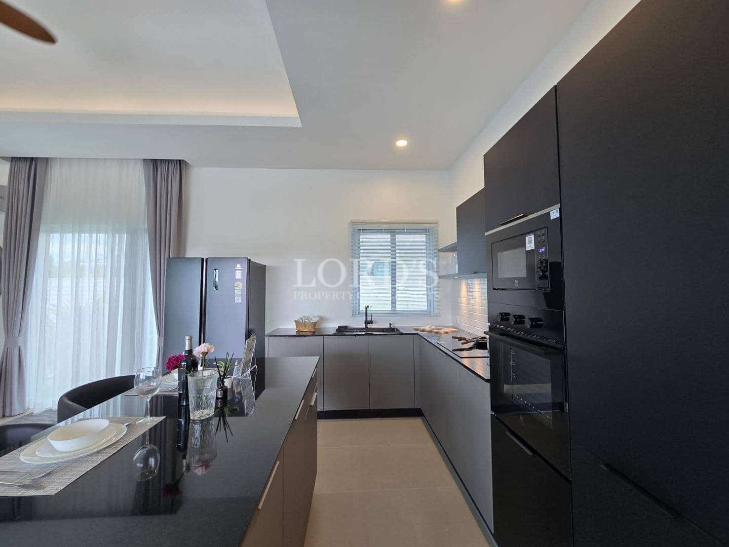Modern kitchen with black cabinetry, built-in appliances, and island dining area.