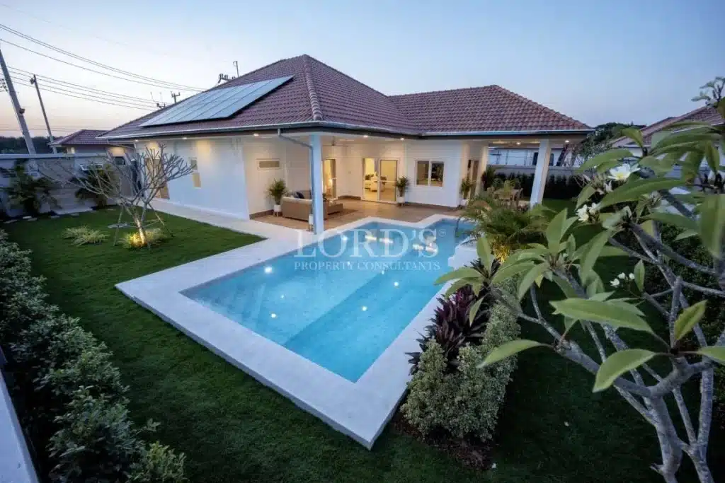 Luxury single-story villa with private swimming pool and landscaped garden at sunset.