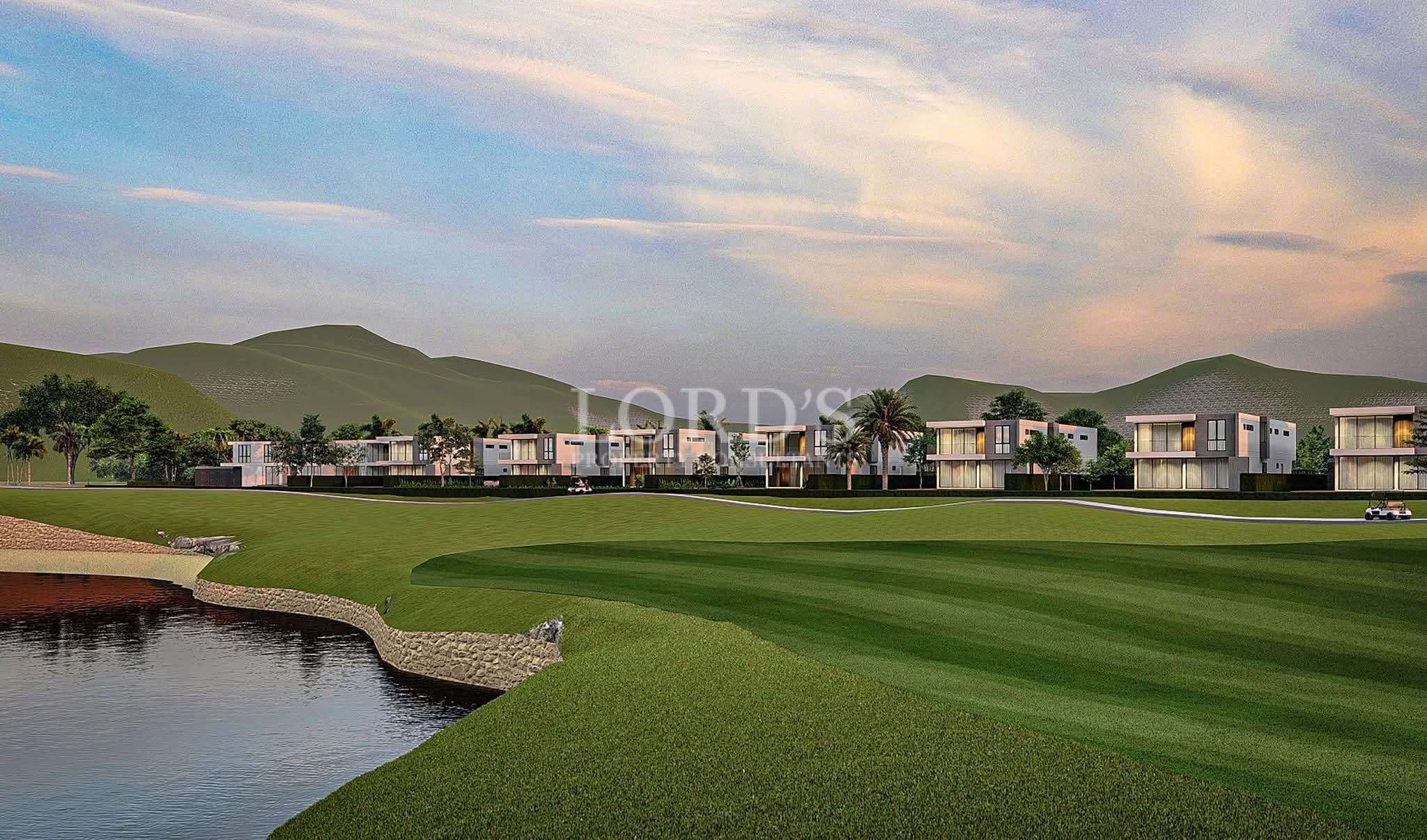 Luxury villa community overlooking a golf course with rolling green fairways, water features, and mountain views at sunset.
