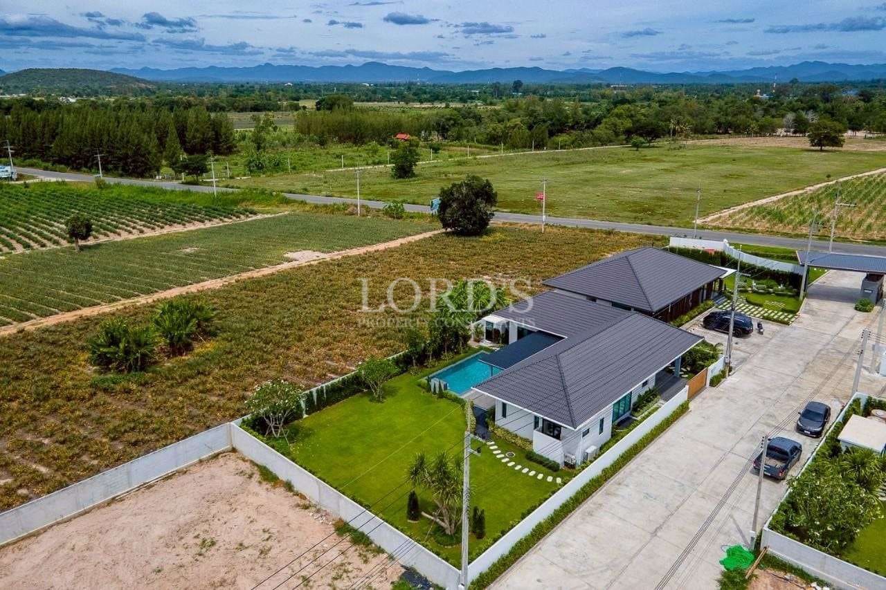 Aerial view of a modern single-story villa with private pool, landscaped garden, and surrounding countryside.