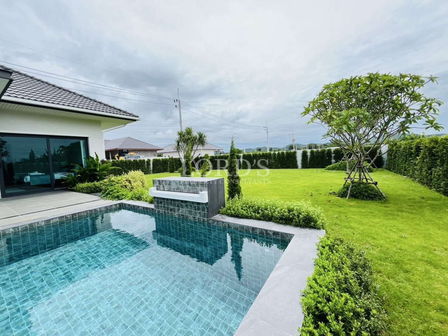 Private swimming pool beside a landscaped garden at a modern single-story villa.