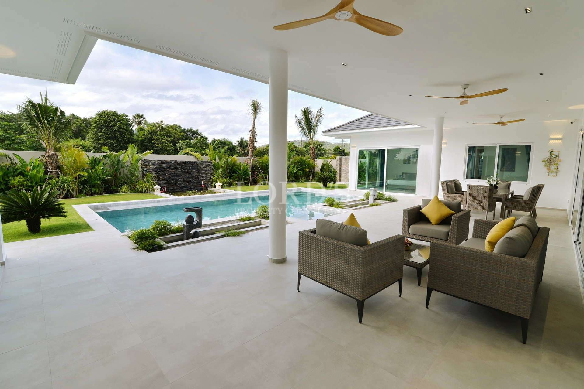 Covered outdoor seating area overlooking a private swimming pool and landscaped tropical garden.