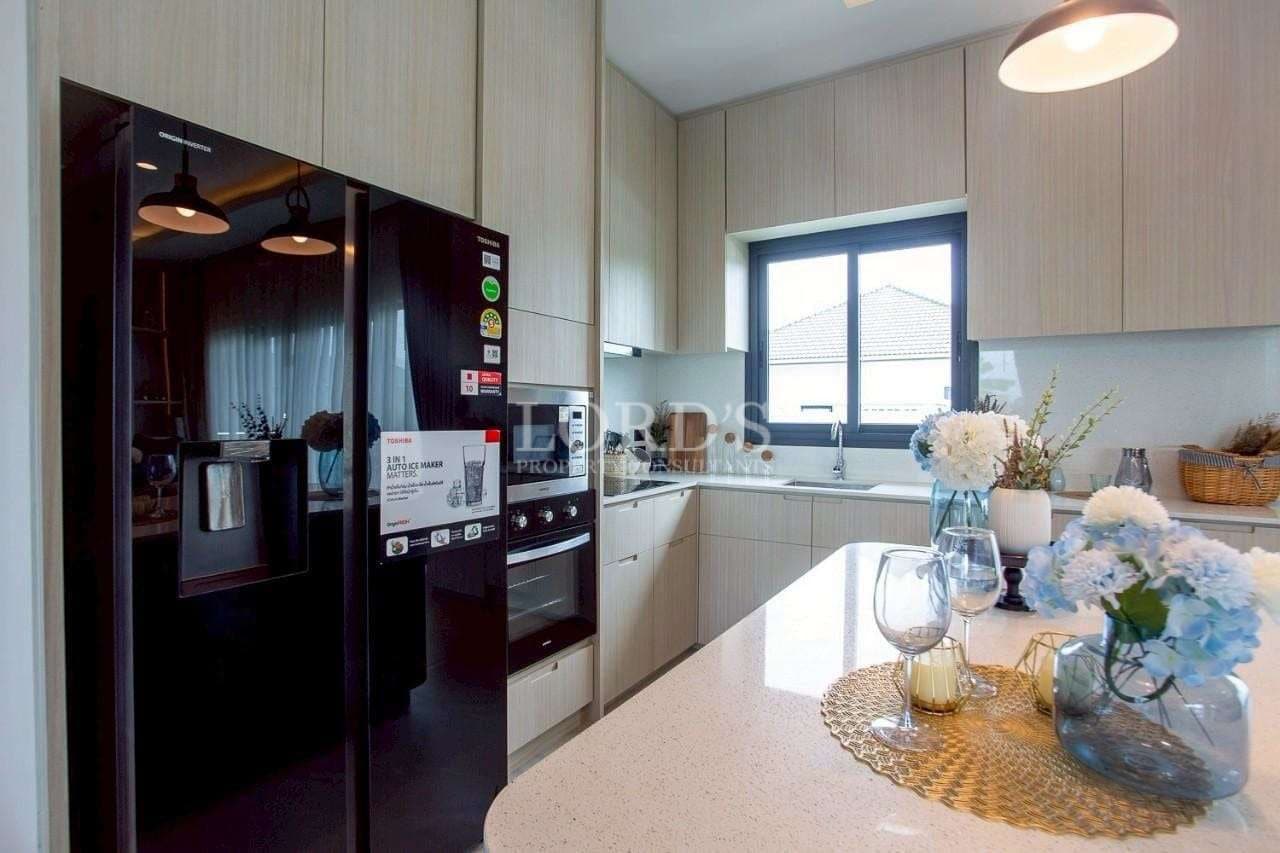 Modern kitchen with integrated black appliances, light wood cabinetry, and a bright island countertop.