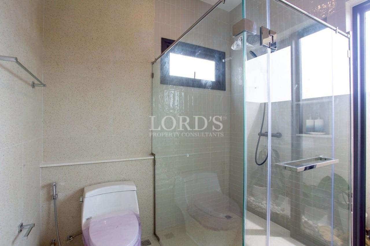 Modern bathroom with glass-enclosed rain shower, minimalist fixtures, and natural light.