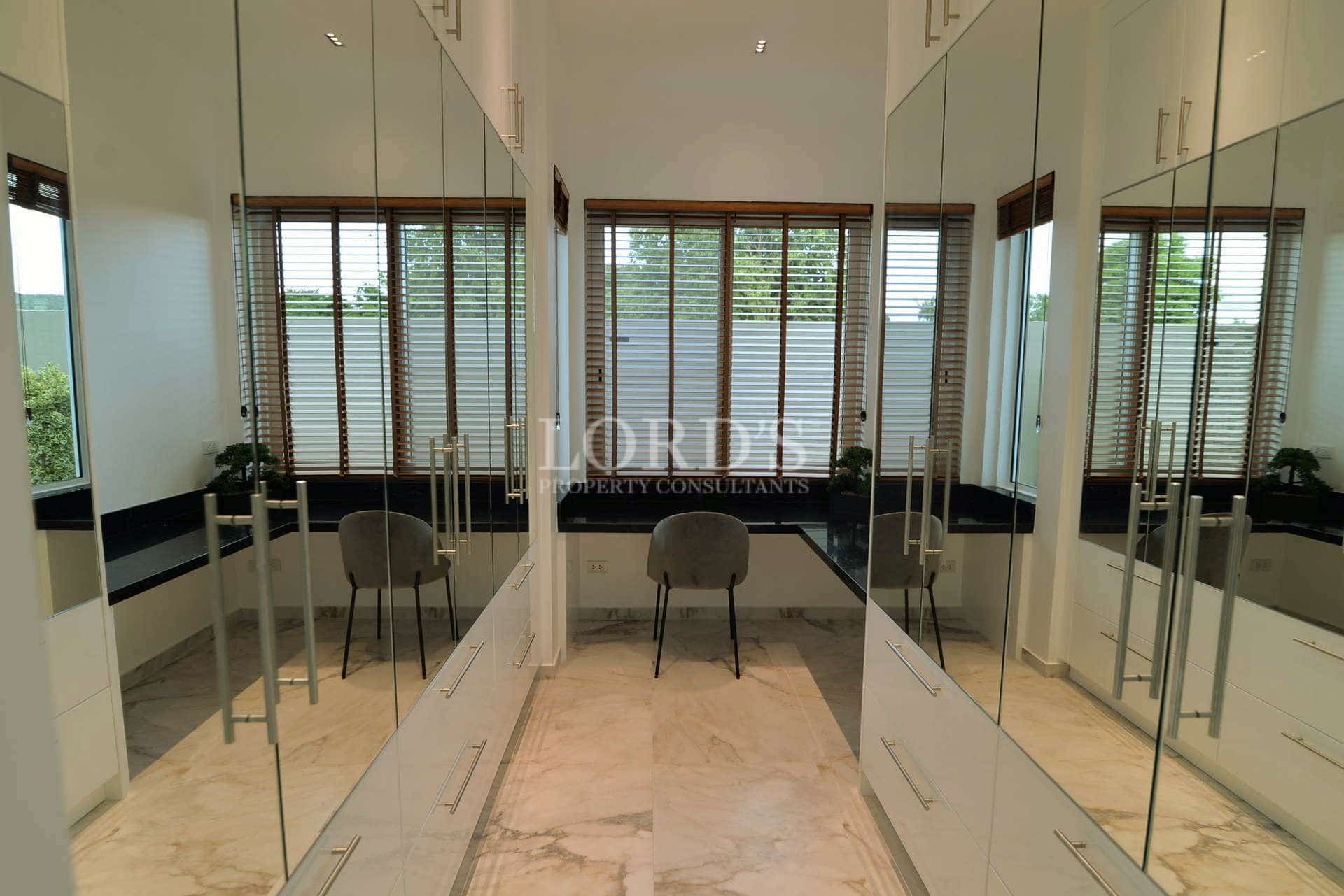 Luxury walk-in wardrobe with mirrored cabinets, marble flooring, and a built-in dressing vanity.