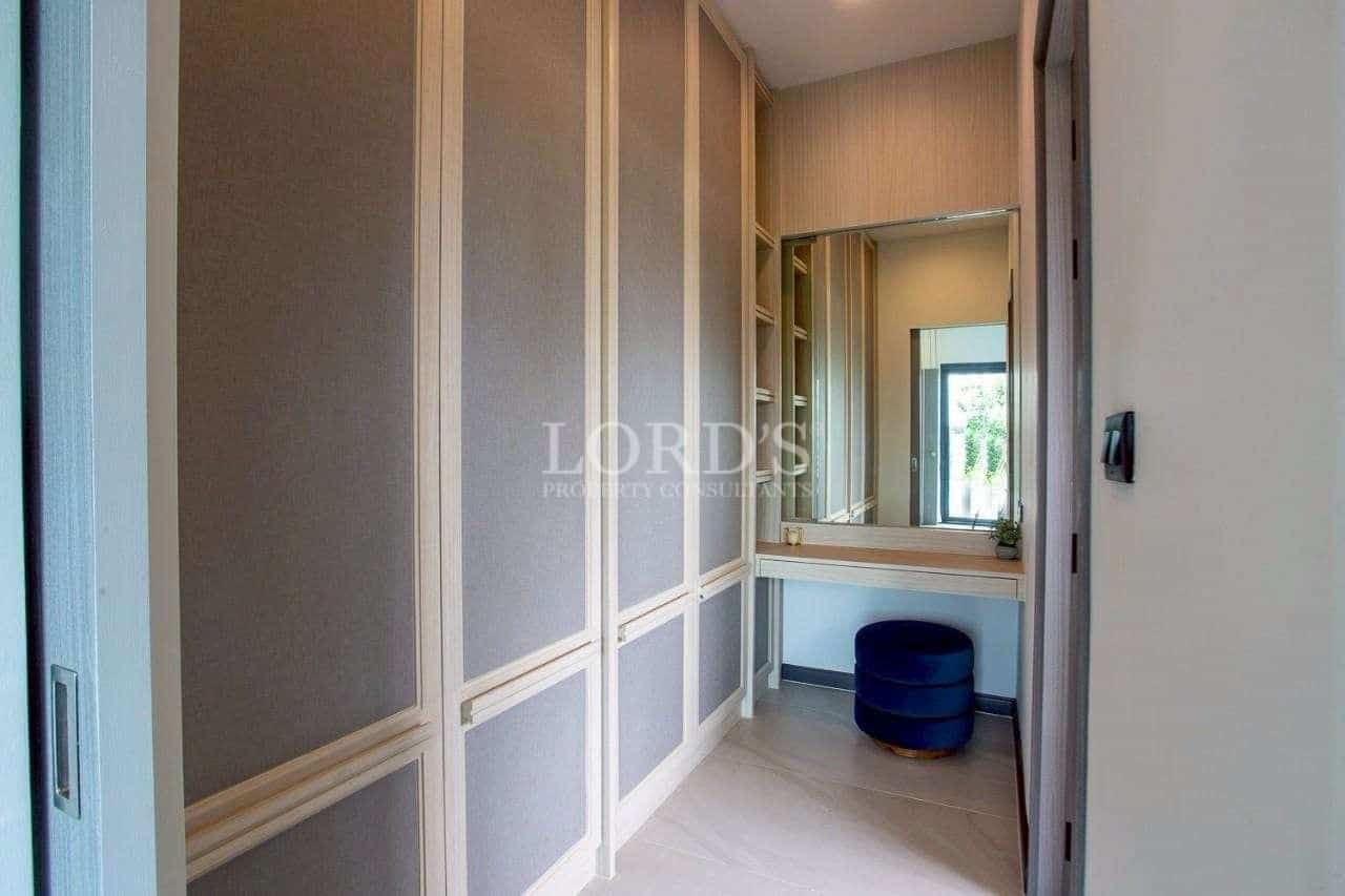 Modern walk-in wardrobe with built-in storage cabinets, vanity mirror, and soft neutral finishes.