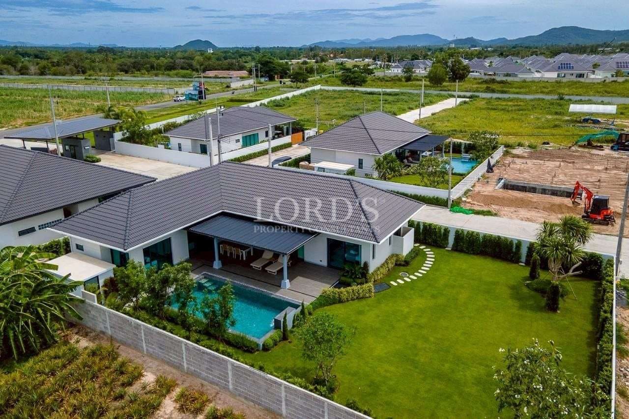 Aerial view of a modern single-story villa with private swimming pool, landscaped garden, and surrounding residential community.