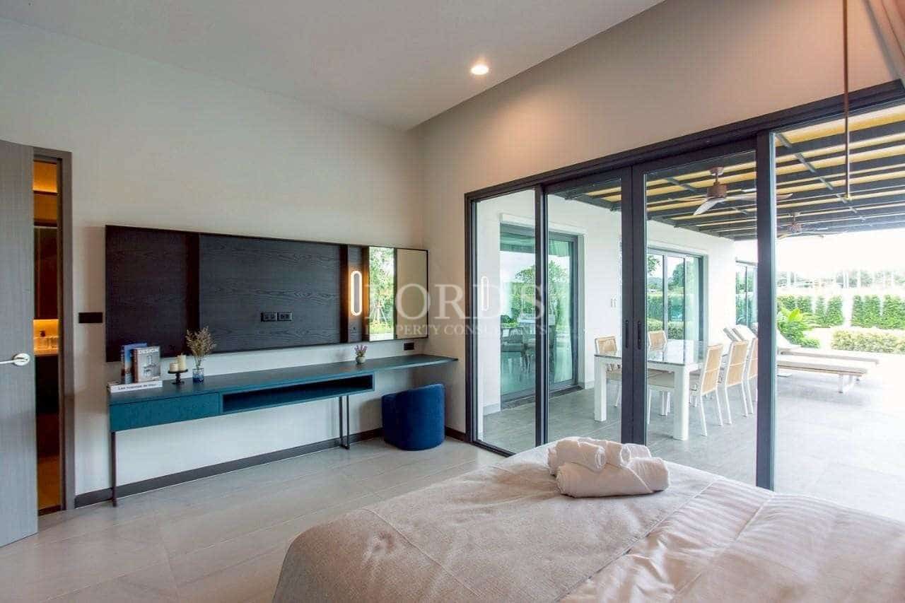 Modern bedroom with sliding glass doors, outdoor terrace access, and minimalist workspace.
