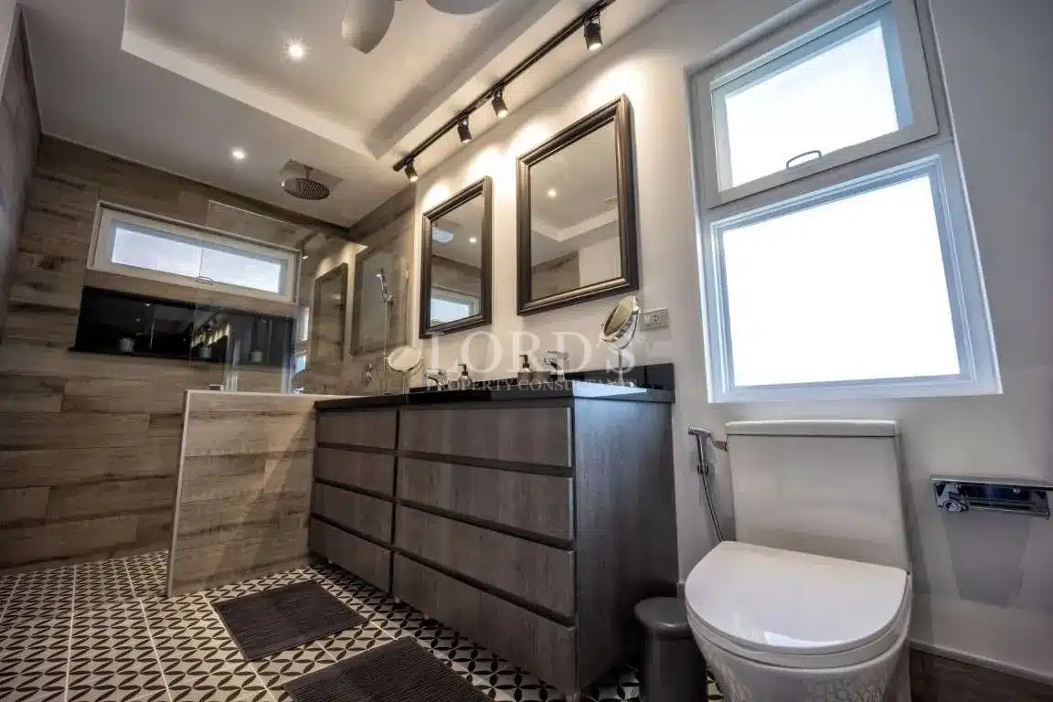 Modern bathroom with double vanity, framed mirrors, walk-in shower, and patterned tile flooring.