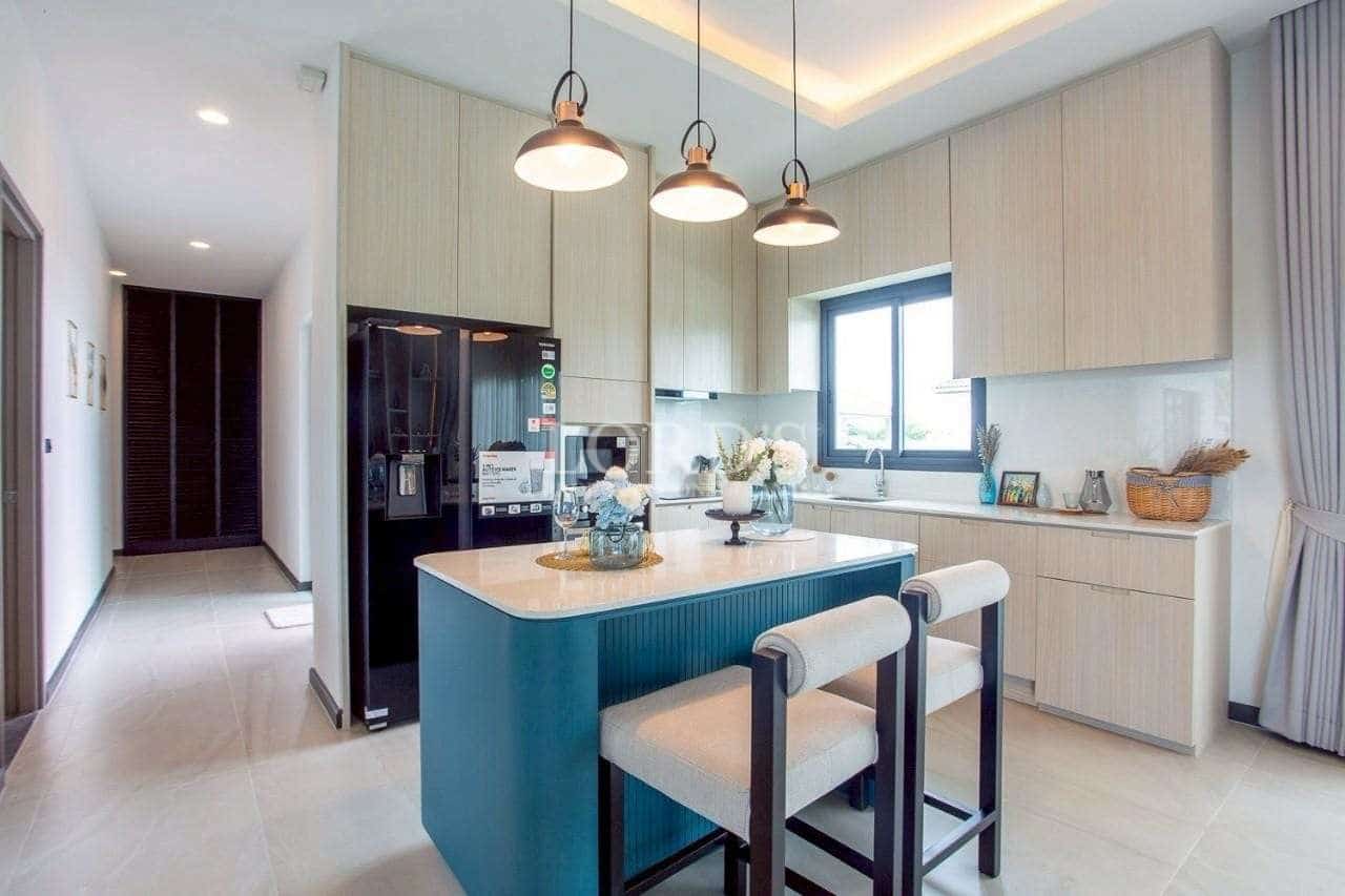 Modern kitchen with blue island, pendant lighting, built-in appliances, and minimalist cabinetry.
