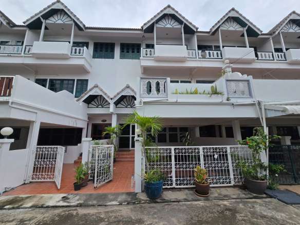 Front exterior of a multi-level townhouse with balconies, white facade, and gated entrance.