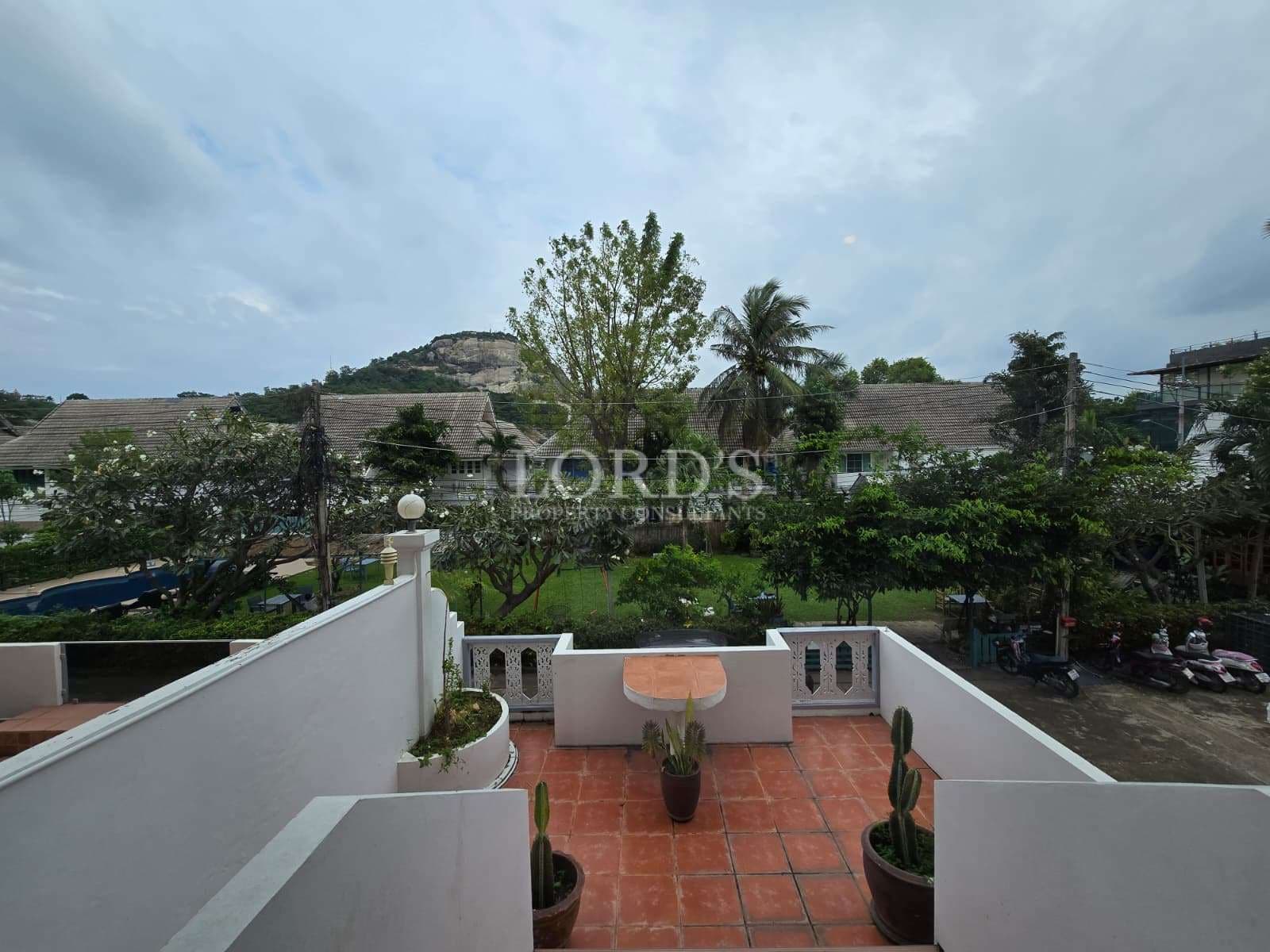 Private terrace with tiled flooring overlooking green trees and hillside surroundings.