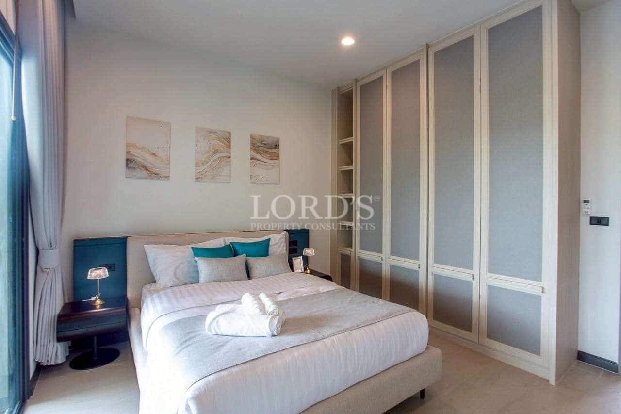 Modern bedroom with upholstered bed, soft neutral tones, and full-height built-in wardrobe.