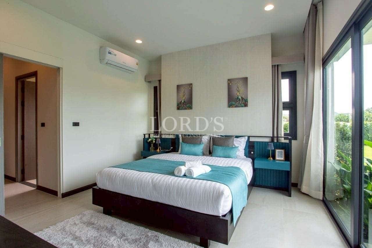 Modern bedroom with teal accents, king-size bed, and large sliding glass doors.