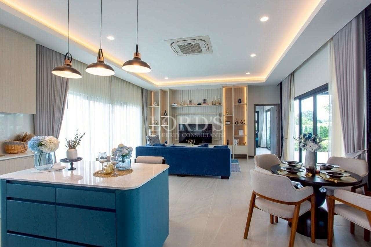 Modern open-plan living and dining area with kitchen island, pendant lighting, and large windows.